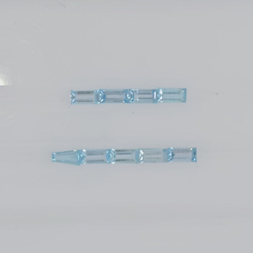 Video of nine rectangular faceted light blue gemstones in two rows on a plain white background
