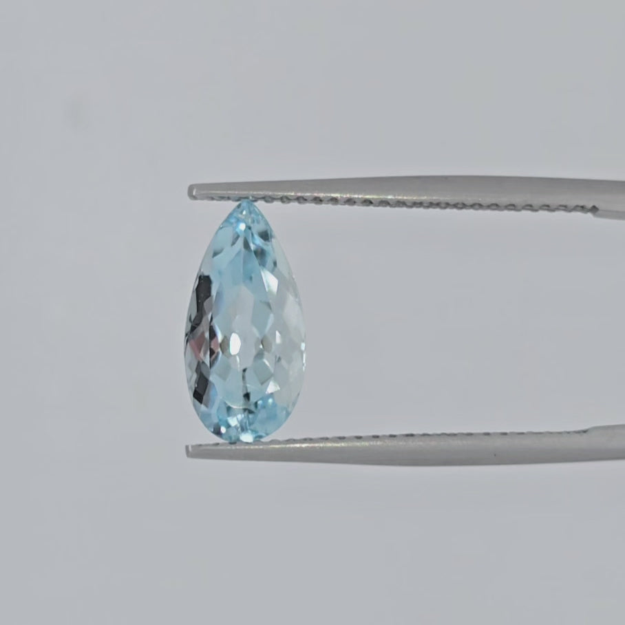 Video of a light blue pear shaped faceted gemstone in tweezers against a plain white background