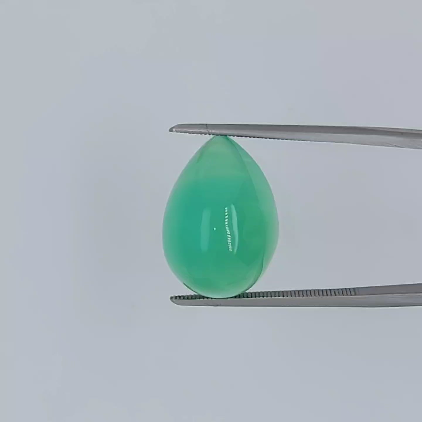 Video of a pear shaped green cabochon gem being shown in tweezers