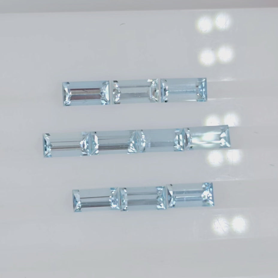 Video of ten light blue faceted rectangular gemstones arranged into three rows on a plain white background