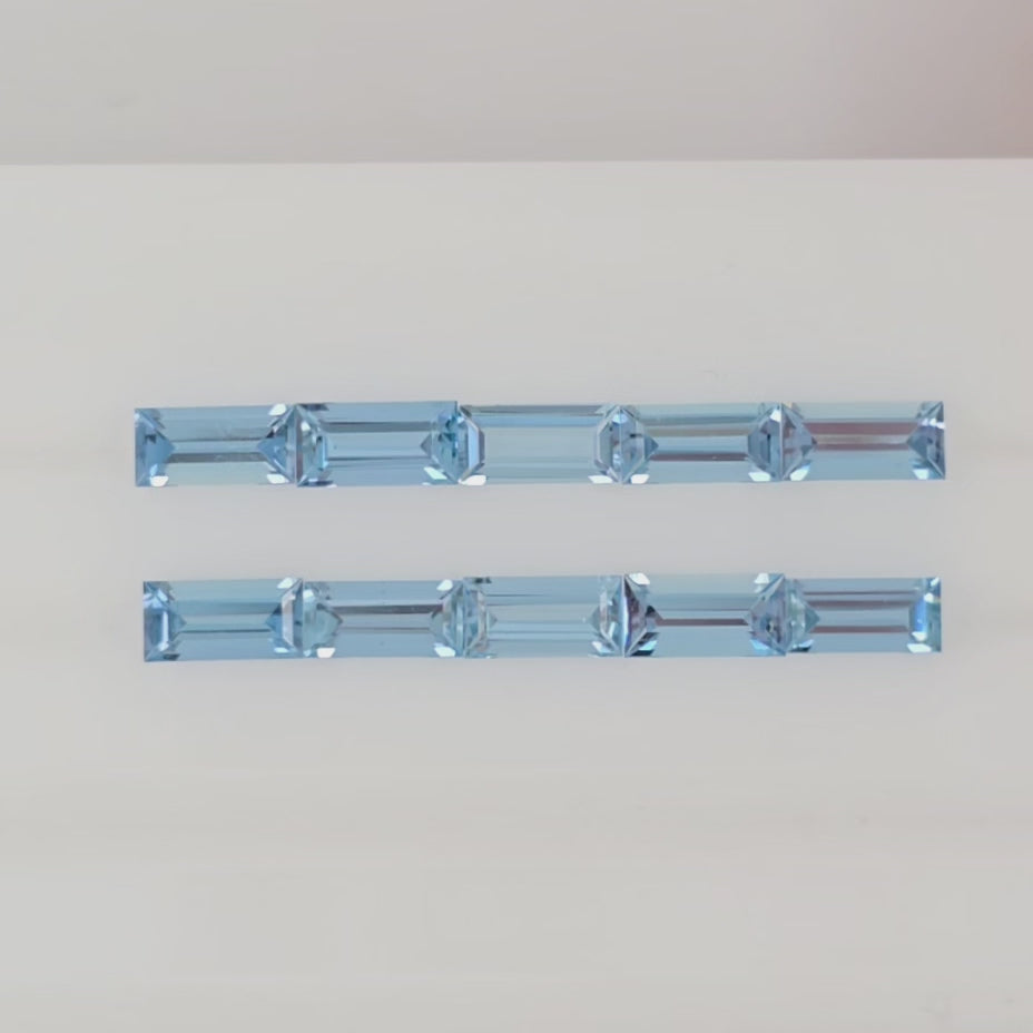 Video of ten baguette cut light blue gemstones arranged in two rows on a plain white background