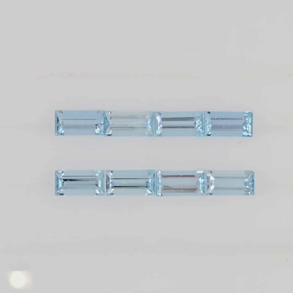Video of 8 light blue baguette cut gemstones arranged in two rows against a plain white background