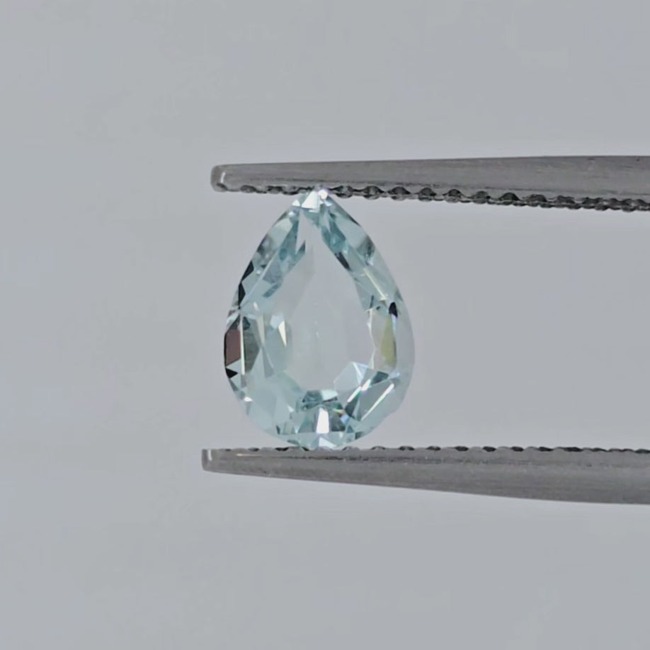 Video of a light blue faceted pear shape gemstone in tweezers against a light background