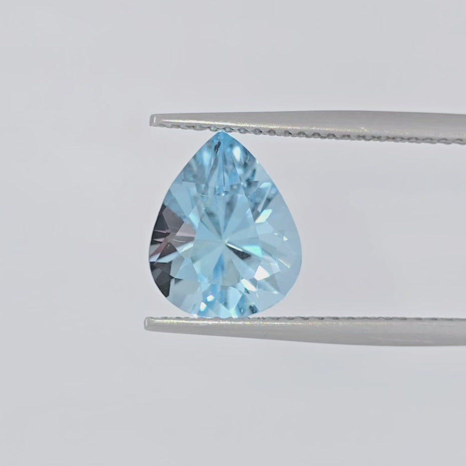 Video of a light blue faceted pear shaped gemstone in tweezers against a plain white background