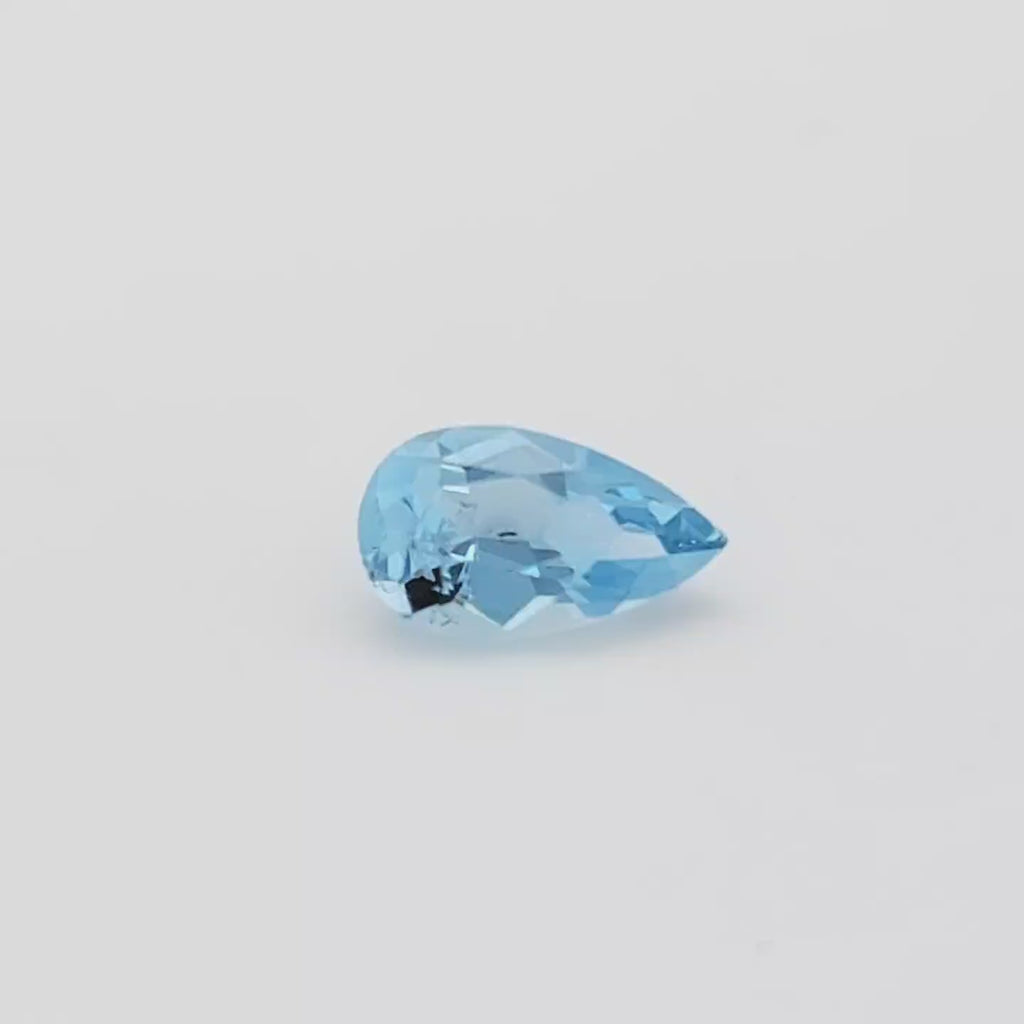 Video of a blue pear shaped faceted gemstone on a white turntable