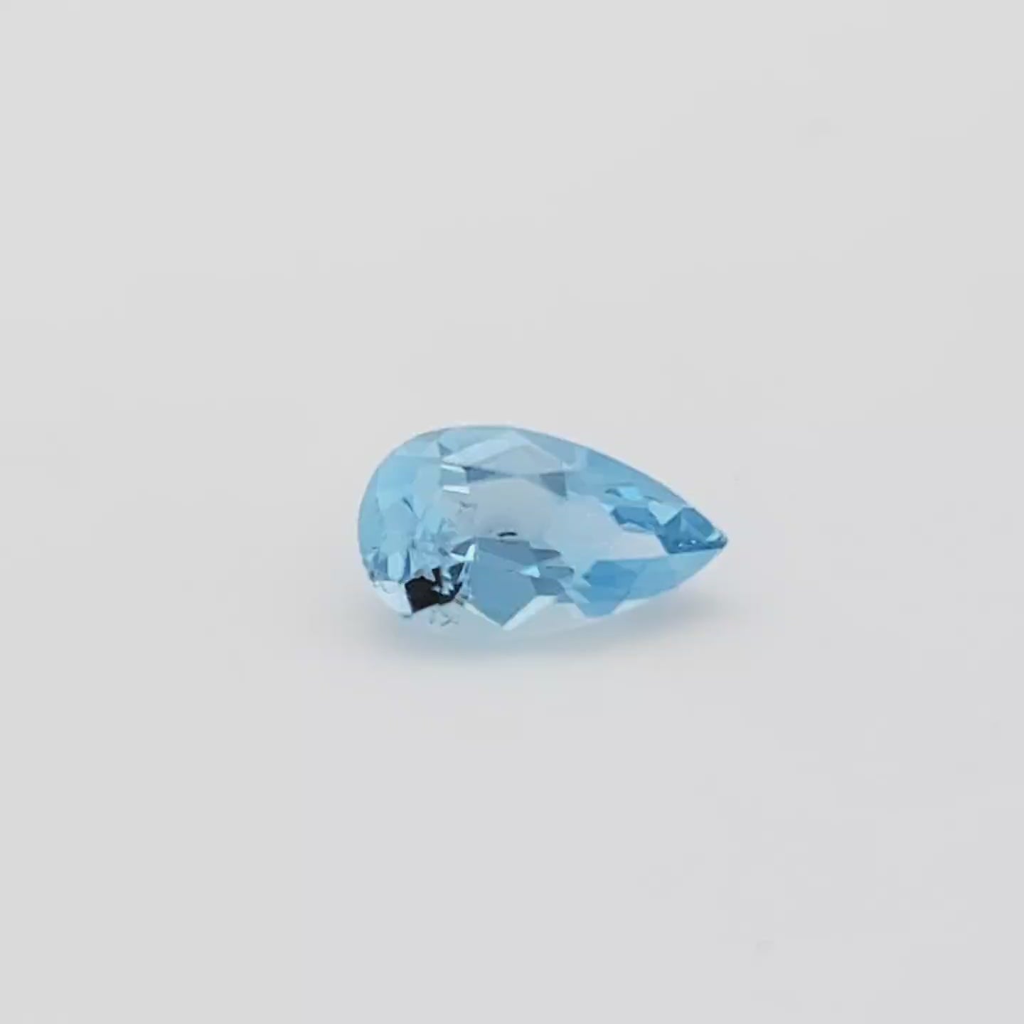 Video of a blue pear shaped faceted gemstone on a white turntable