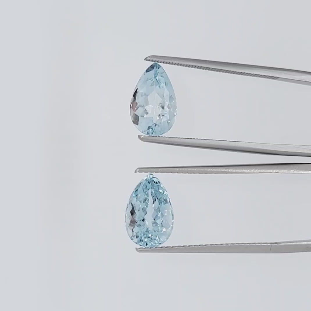 Video of two pear shaped light blue gemstones in tweezers against a plain white background